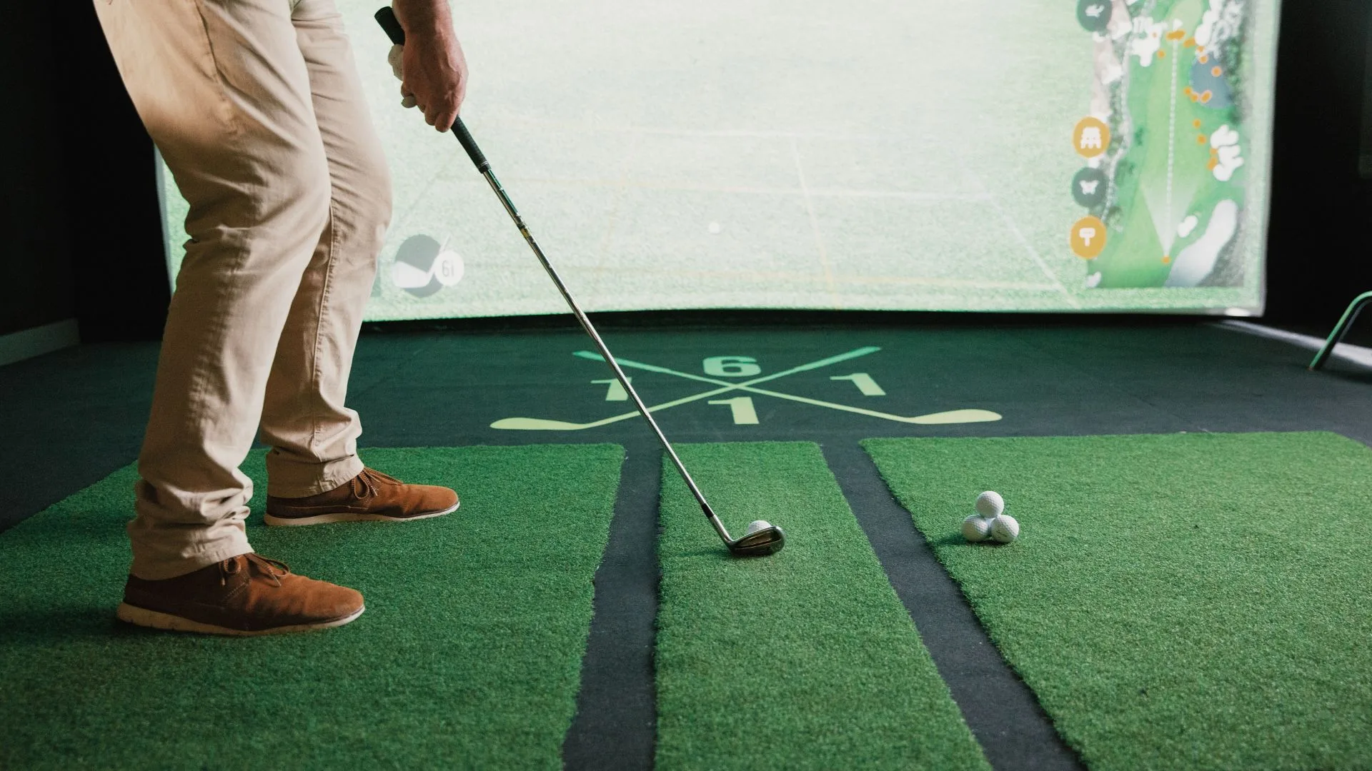 Golfer mid-swing with TrackMan on screen